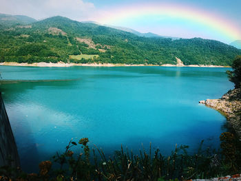 Scenic view of lake by mountains against sky