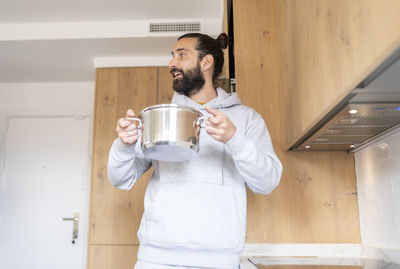 Mid adult man holding drink standing at home