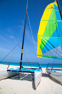 Sailboats moored at beach against sky