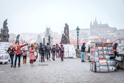 People walking on street in city against sky during winter