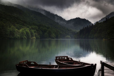 Boat moored on lake against sky