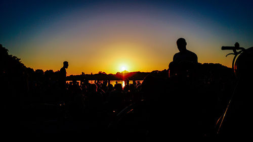 Silhouette people at music concert against sky during sunset