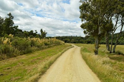 Road amidst field against sky