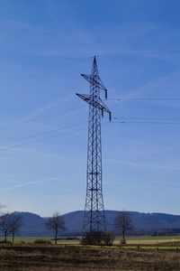 Low angle view of electricity pylon on field against sky