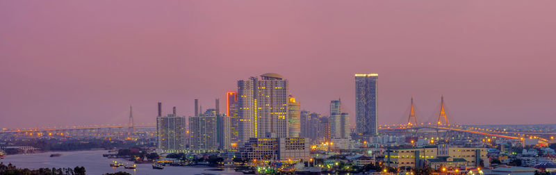 Illuminated buildings in city at sunset