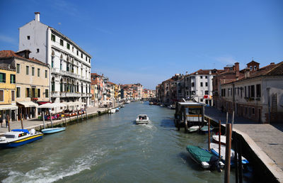 Boats in canal amidst buildings in city