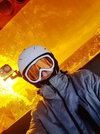 Low section of man wearing hat standing against yellow wall