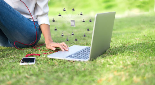 Midsection of man using mobile phone in grass