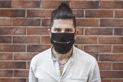 Portrait of person wearing mask against brick wall