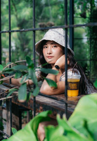 Portrait of woman with drink seen through metal grate