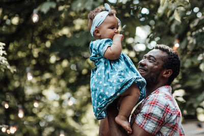 Father and daughter with baby tree against blurred background