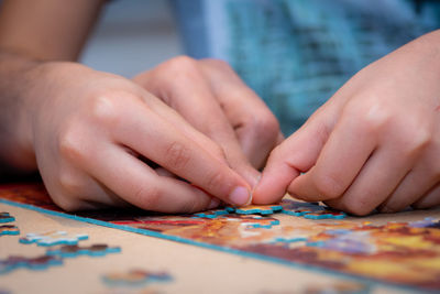 Cropped hands of people playing jigsaw puzzle