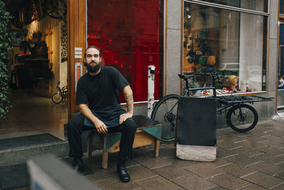 Full length portrait of young man sitting on seat