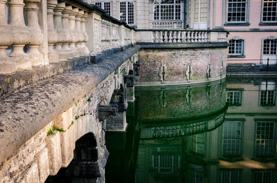 Historic building by bridge reflecting on canal in city