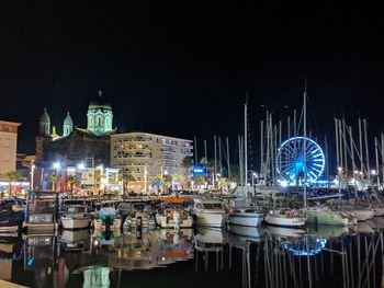 Boats moored in illuminated city against clear sky at night