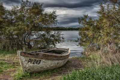 Abandoned boat moored by lake against sky