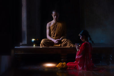 Woman sitting on table at illuminated temple