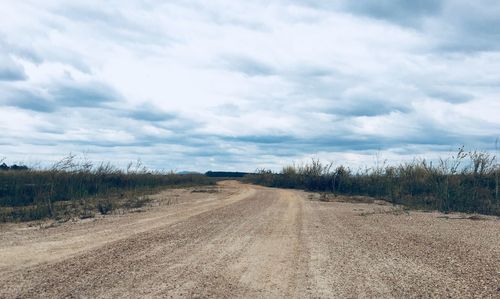 Road amidst field against sky