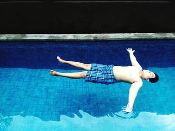 Full length of shirtless man swimming in pool