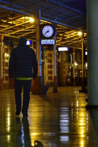 Rear view of man walking in illuminated subway station