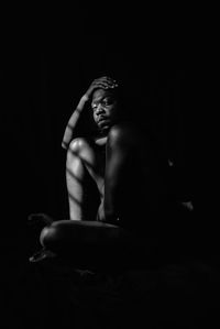 Naked man sitting in dark