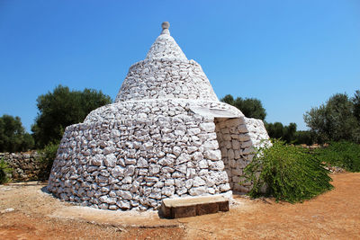 Stack of stone wall against clear blue sky