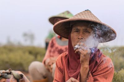 Senior woman smoking marijuana joint at farm