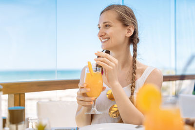 Young woman drinking from glass while sitting on table