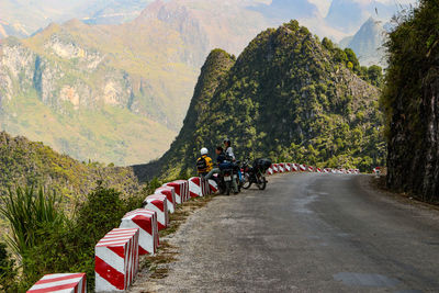 People riding bicycle on road amidst trees