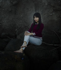 Full length of woman sitting on rock