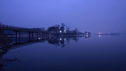 Illuminated bridge over lake against sky at night