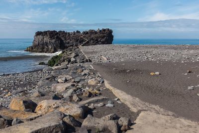 Scenic view of rocks on beach against sky