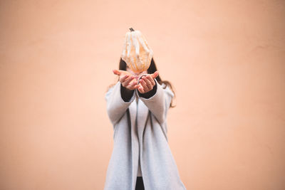 Midsection of man holding ice cream against wall