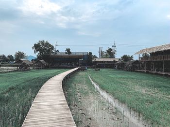 Empty footpath amidst buildings against sky