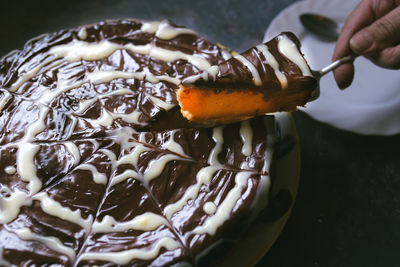 Cropped hand of person holding chocolate cake on table