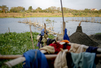 People at riverbank against sky