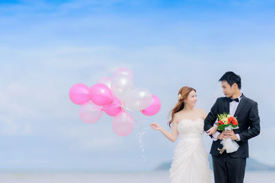 Bride and groom standing against sky