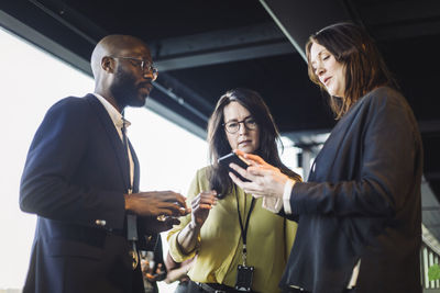 Female entrepreneur showing mobile phone to colleagues in office