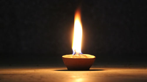 Close-up of lit candle against black background