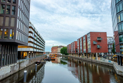 Canal amidst buildings in city against sky