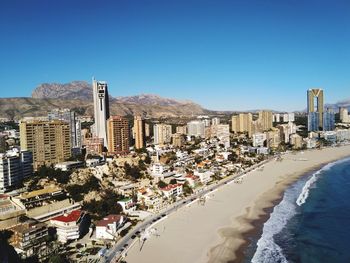 Panoramic view of beach and buildings against clear blue sky