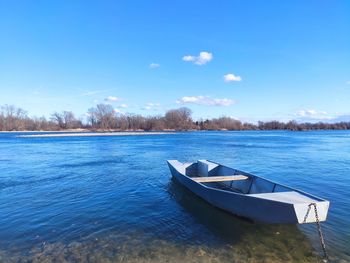 Boat moored on lake against blue sky