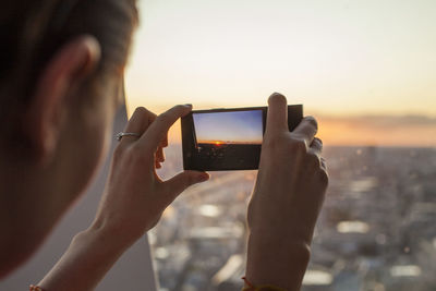 Man photographing through smart phone against sky