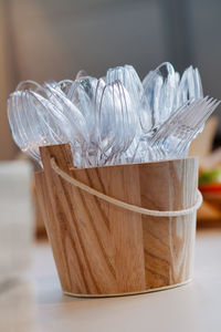 Close-up of plastic spoons and fork in wooden bucket