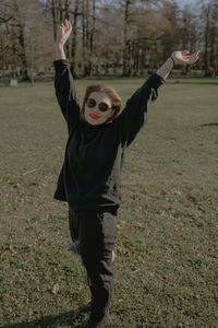Rear view of woman with arms raised standing on field