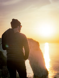 Rear view of man standing against sky during sunset