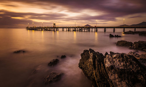 Jetty at calm sea against clouds