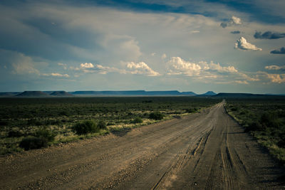 Road by landscape against sky during sunset