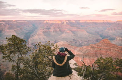 Rear view of person sitting on rock against grand canyon national park