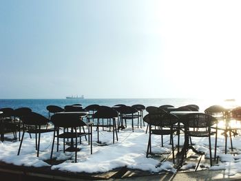 Chairs and table on beach against clear sky